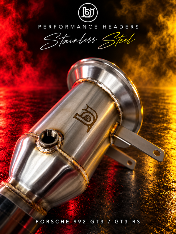 Close-up of a BJG stainless steel Porsche 992 GT3/GT3 RS header outlet section, showing logo, welds, sensor bung, flange and open mounting tabs under red and yellow lighting.
